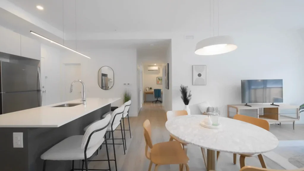 Cuisine et salle à manger moderne avec îlot central, table ronde et canapé confortable.