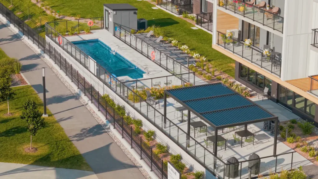 Piscine extérieure avec chaises longues et pergola dans un complexe résidentiel moderne.